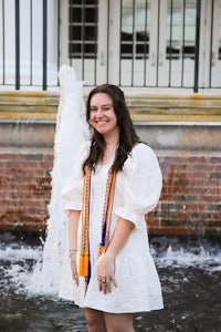 a woman in a white dress standing in front of a fountain