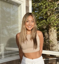 a woman in a tan crop top and white pants
